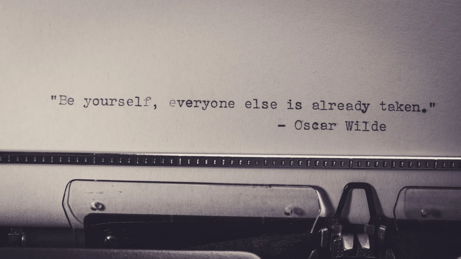 Vintage typewriter displaying Oscar Wilde's quote 'Be yourself, everyone else is already taken.'. Why U.S. business and tech quotes get misattributed so often