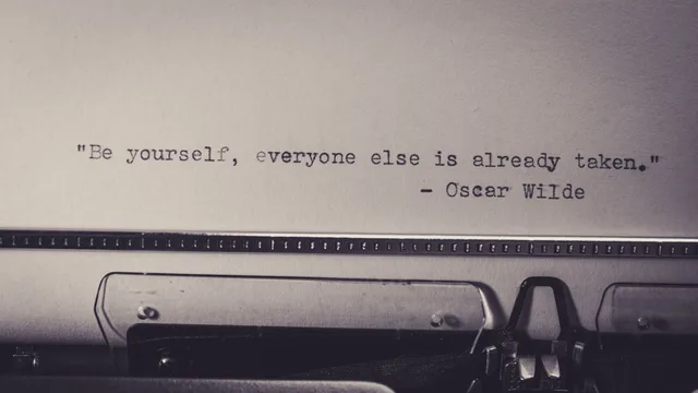 Vintage typewriter displaying Oscar Wilde's quote 'Be yourself, everyone else is already taken.'. Why U.S. business and tech quotes get misattributed so often