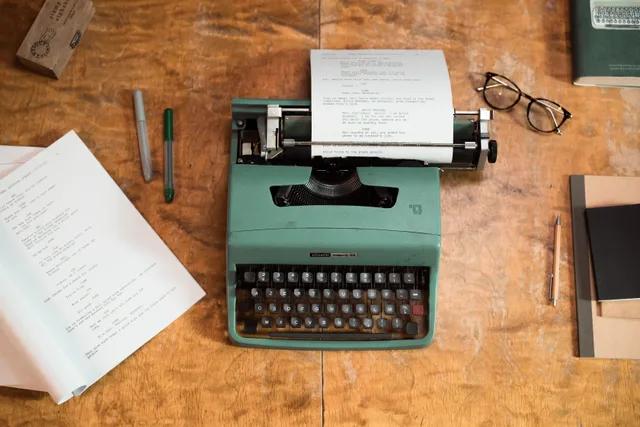 A vintage green typewriter with scripts surrounded by glasses and pens on a wooden table. Correcting misquotes after a fact check: four repairs and what the note must say