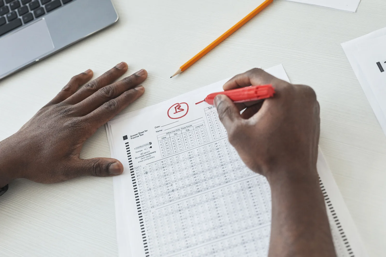 Close-up of a teacher grading multiple choice exams with a red pen on a desk. Misquotes and fact checks analysis: a grading scale
